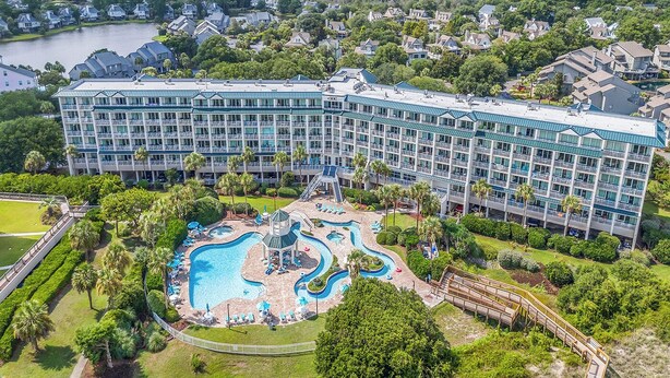 A large hotel with a central swimming pool, multiple balconies, and lush greenery surrounding the property. - Welcome to Coastal Calm at Bridgewater 
Oceanfront at LBTS at Pawleys Island (Pawleys Island)