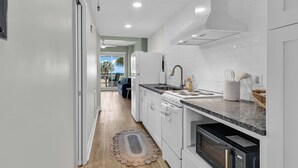 A modern kitchen with white cabinetry, a granite countertop, and a view to the outside. - Welcome to Coastal Calm at Bridgewater 
Oceanfront at LBTS at Pawleys Island (Pawleys Island)
