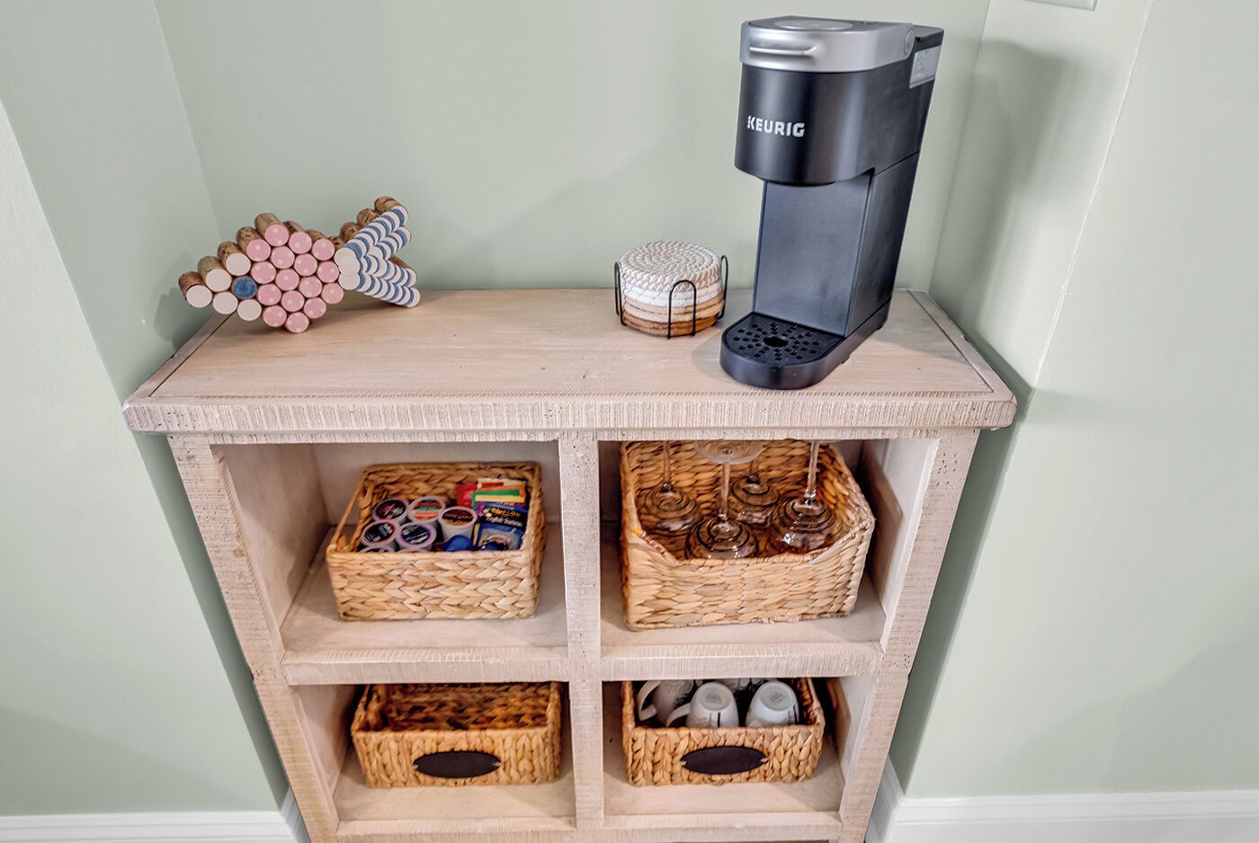 A wooden shelf with a Keurig coffee maker, a decorative item, and baskets containing various items.