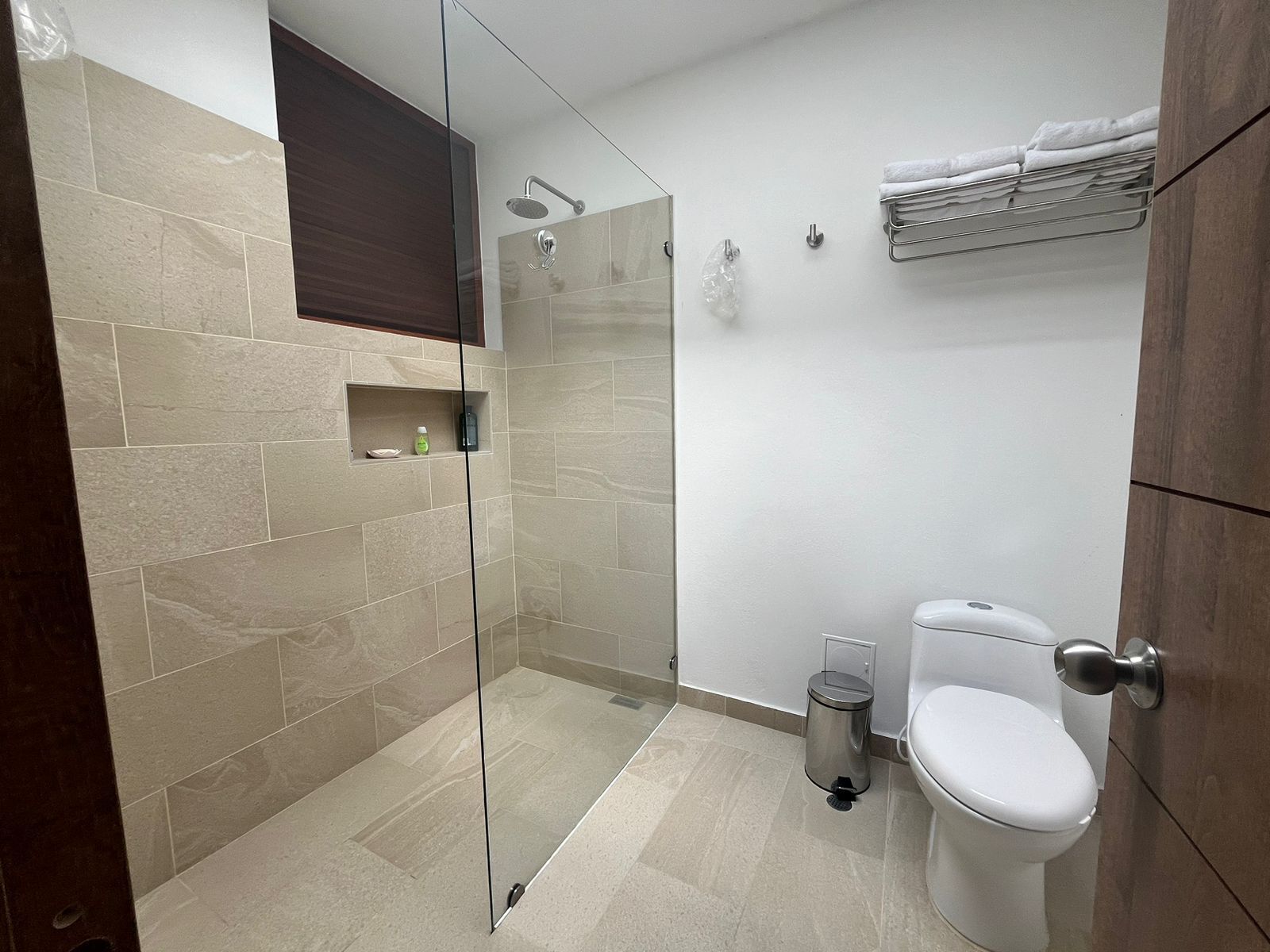 A modern bathroom with a glass shower enclosure, a toilet, and a towel rack.