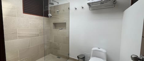 A modern bathroom with a glass-enclosed shower, a toilet, and a towel rack.