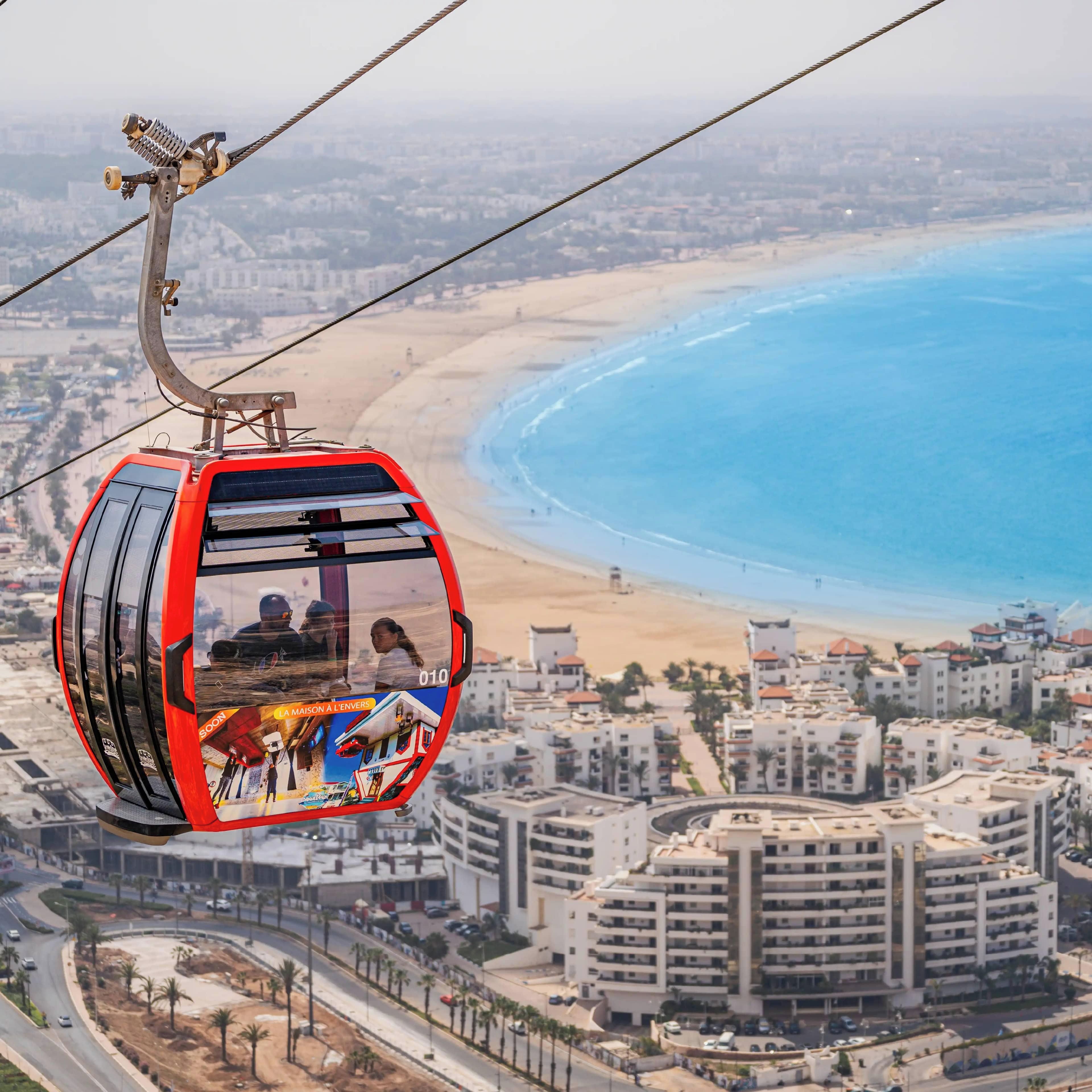 A cable car with a panoramic view of a beach and cityscape.