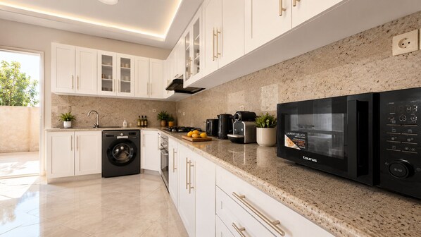 A modern kitchen with white cabinetry, a built-in washer, a black microwave, and a granite countertop. - Villa with private pool - total calm near Agadir (Agadir)