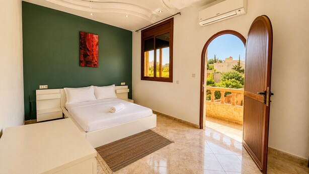 A bedroom with a bed, a bedside table, a window, and a door leading to a balcony. - Villa with private pool - total calm near Agadir (Agadir)