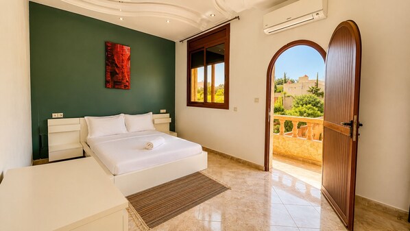 A bedroom with a bed, a bedside table, a window, and a door leading to a balcony. - Villa with private pool - total calm near Agadir (Agadir)