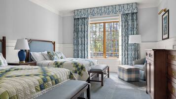 A bedroom with two beds, a dresser, a window with curtains, and a lamp.