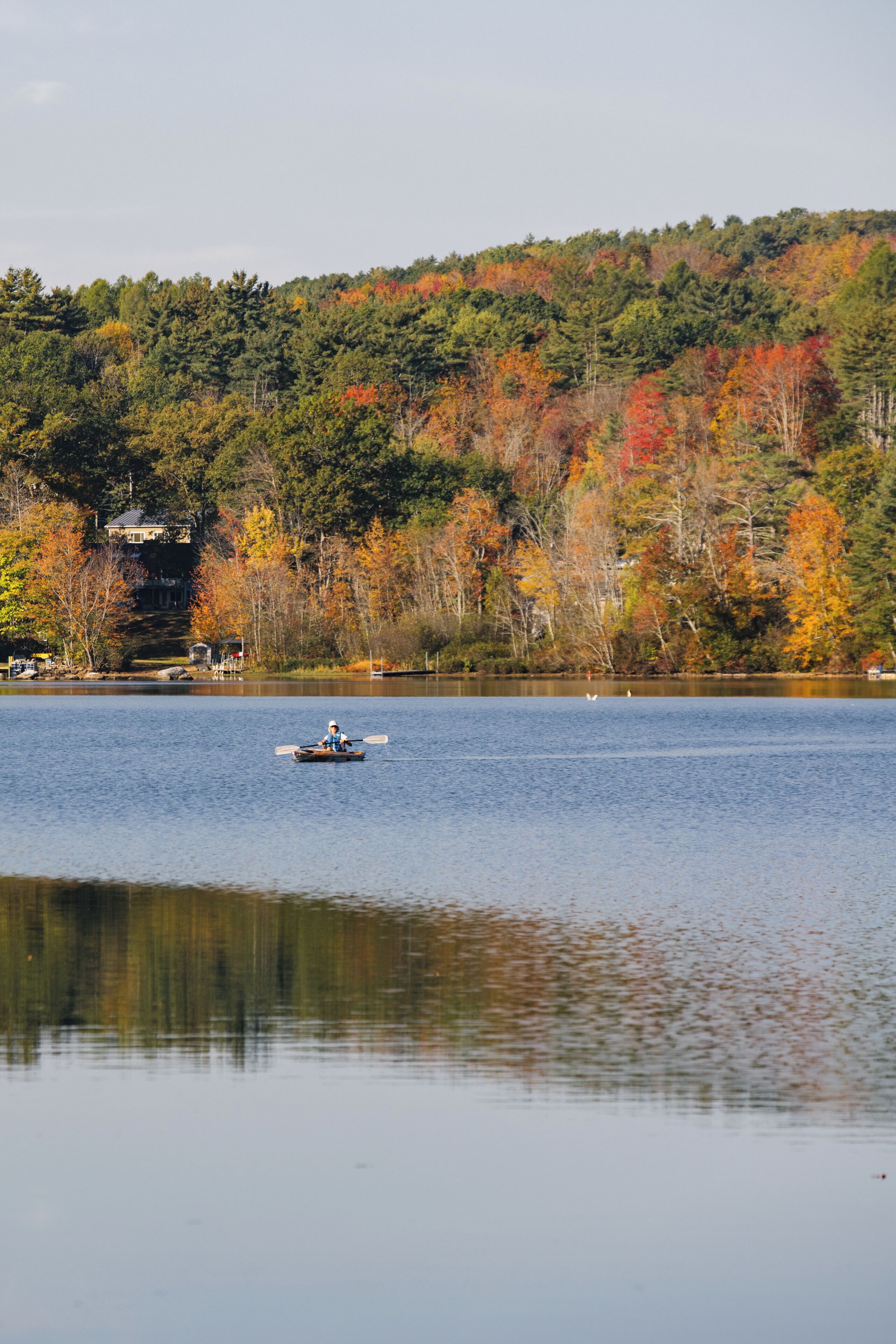 A calm lake with a boat in the foreground and a forested hill in the background.