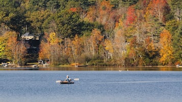 A calm lake with a boat in the foreground and a forested hill in the background.