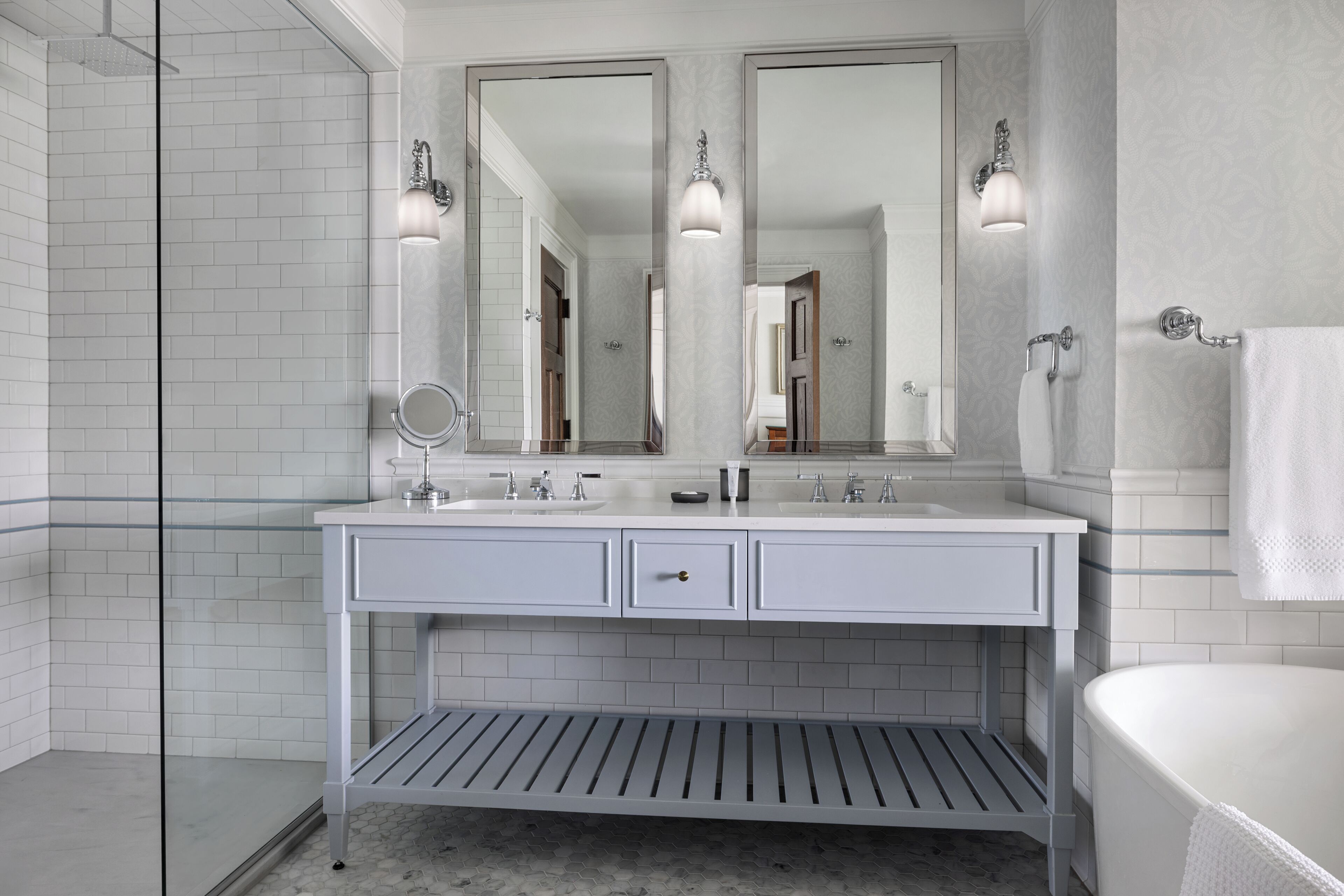 A bathroom with a white vanity, two mirrors, a sink, and a shower area.