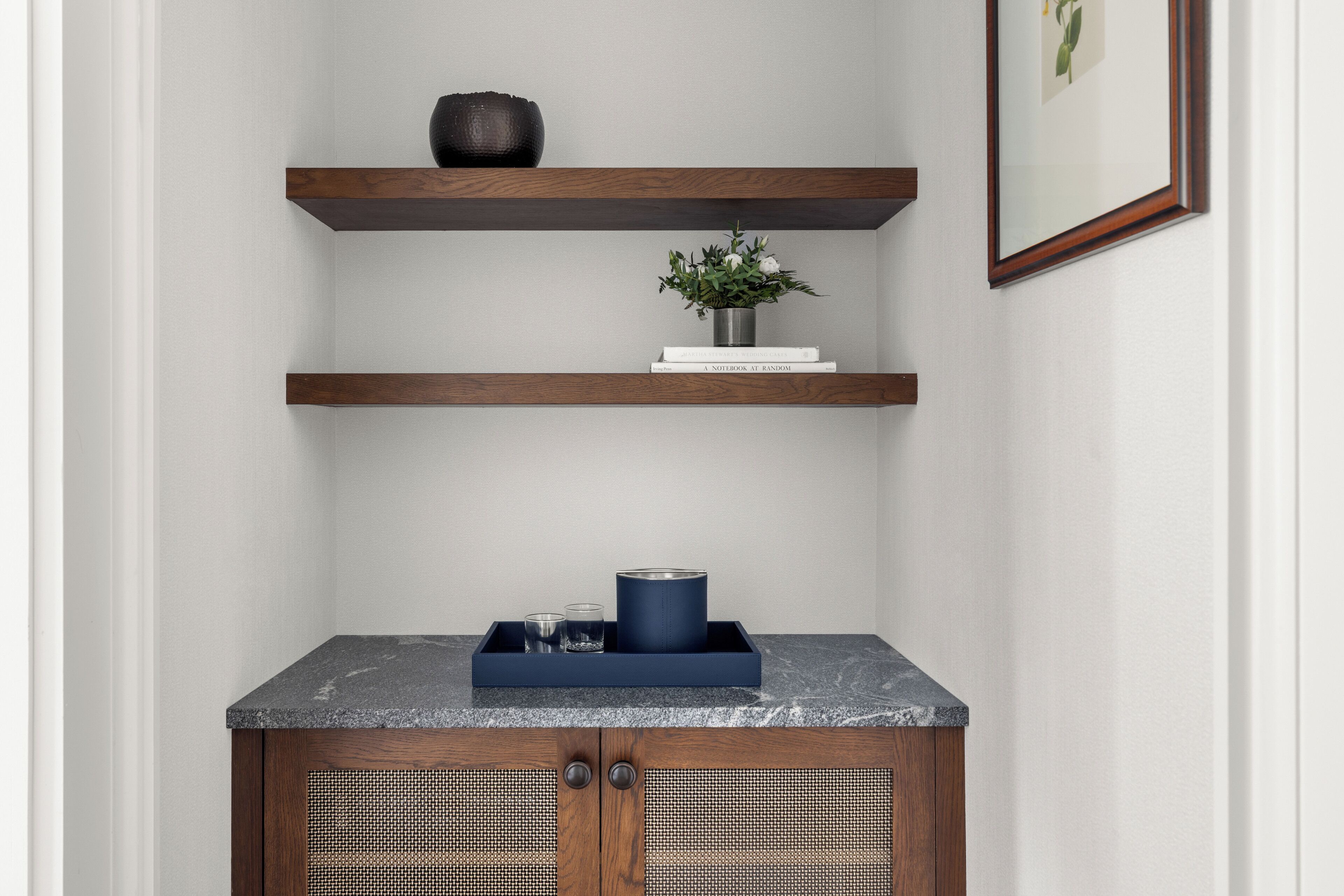 A corner with a wooden cabinet and two shelves above it.