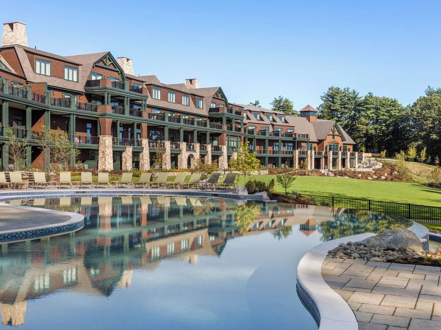 A hotel with a large pool, multiple balconies, and a well-maintained lawn.