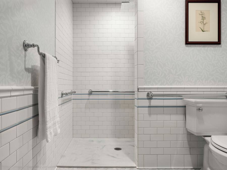 A modern bathroom with white subway tiles, a glass shower enclosure, a toilet, and a framed botanical print on the wall.