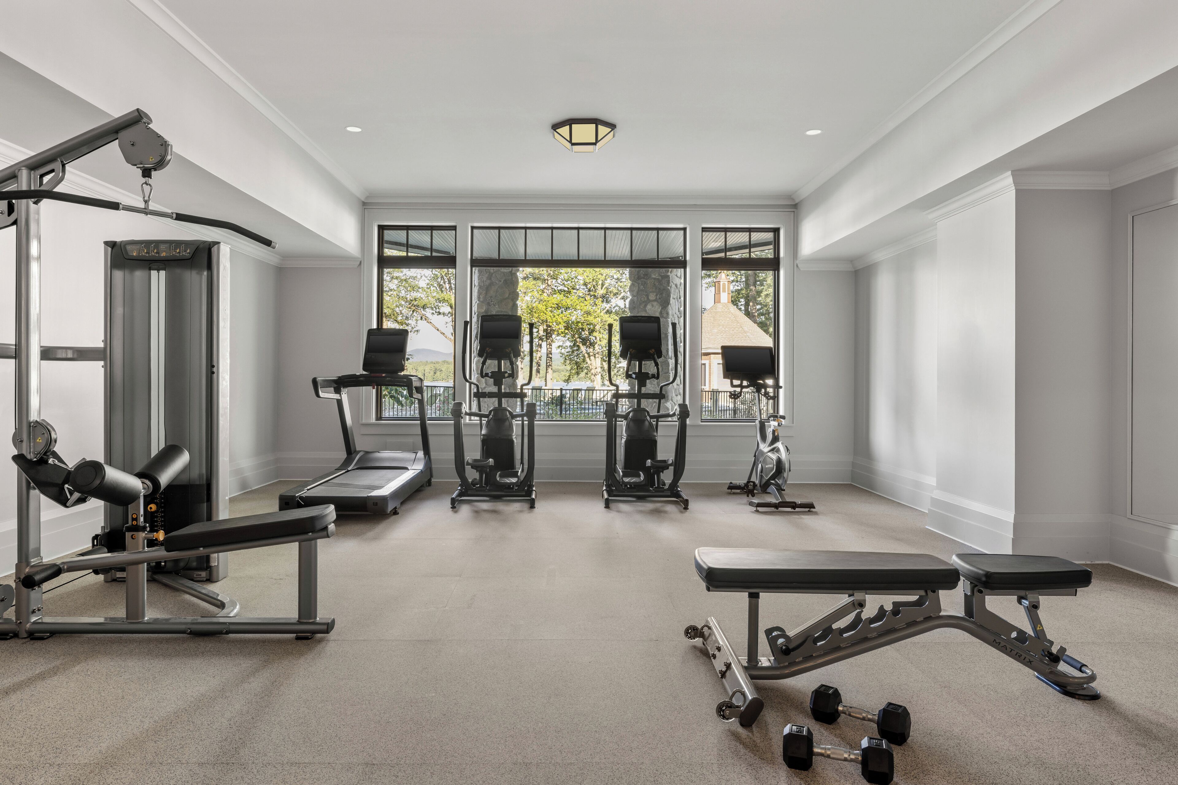 Une salle de sport spacieuse équipée de machines de cardio, de bancs de musculation et d’haltères.
