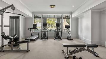 Une salle de sport spacieuse équipée de machines de cardio, de bancs de musculation et d’haltères.