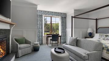 Una habitación de hotel con chimenea, una cama con dosel, un sofá, una silla y un escritorio.