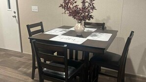 A dining area with a table set for four, surrounded by chairs, and a vase with flowers on the table. - 3-bedroom mobile home in Florence, SC (Florence)
