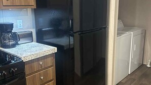A modern kitchen with a black refrigerator, wooden cabinets, a built-in oven, and a coffee maker. - 3-bedroom mobile home in Florence, SC (Florence)
