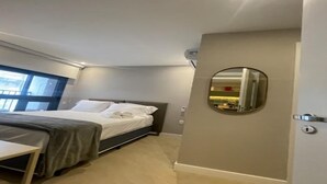 Ein modernes Schlafzimmer mit einem Bett, einem Nachttisch und einem runden Spiegel an der Wand.