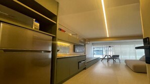 Eine moderne Küche mit einem Edelstahlkühlschrank, dunklen Schränken und einer hellen Deckenleuchte.