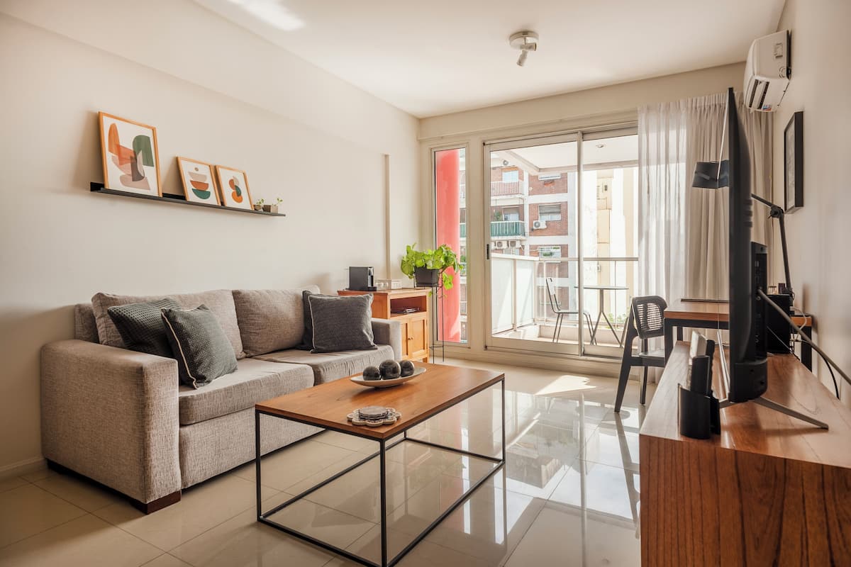 A modern living room with a sofa, coffee table, and a dining area with a chair and table.