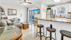 A modern kitchen with a large island, bar stools, and a dining area with a glass-top table. - Beachside Villas 613 (Santa Rosa Beach)