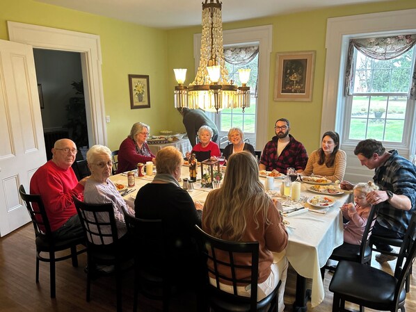 A dining room with a chandelier, a table set for a meal, and a view of the outdoors through a window. - Harmony Forge Inn (Milesburg)