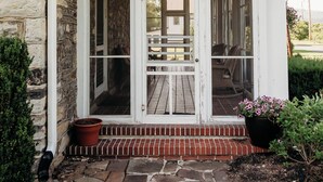 A stone building with a white porch and a covered entryway. - Harmony Forge Inn (Milesburg)