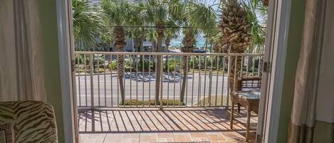A balcony with a view of palm trees and a parking area.