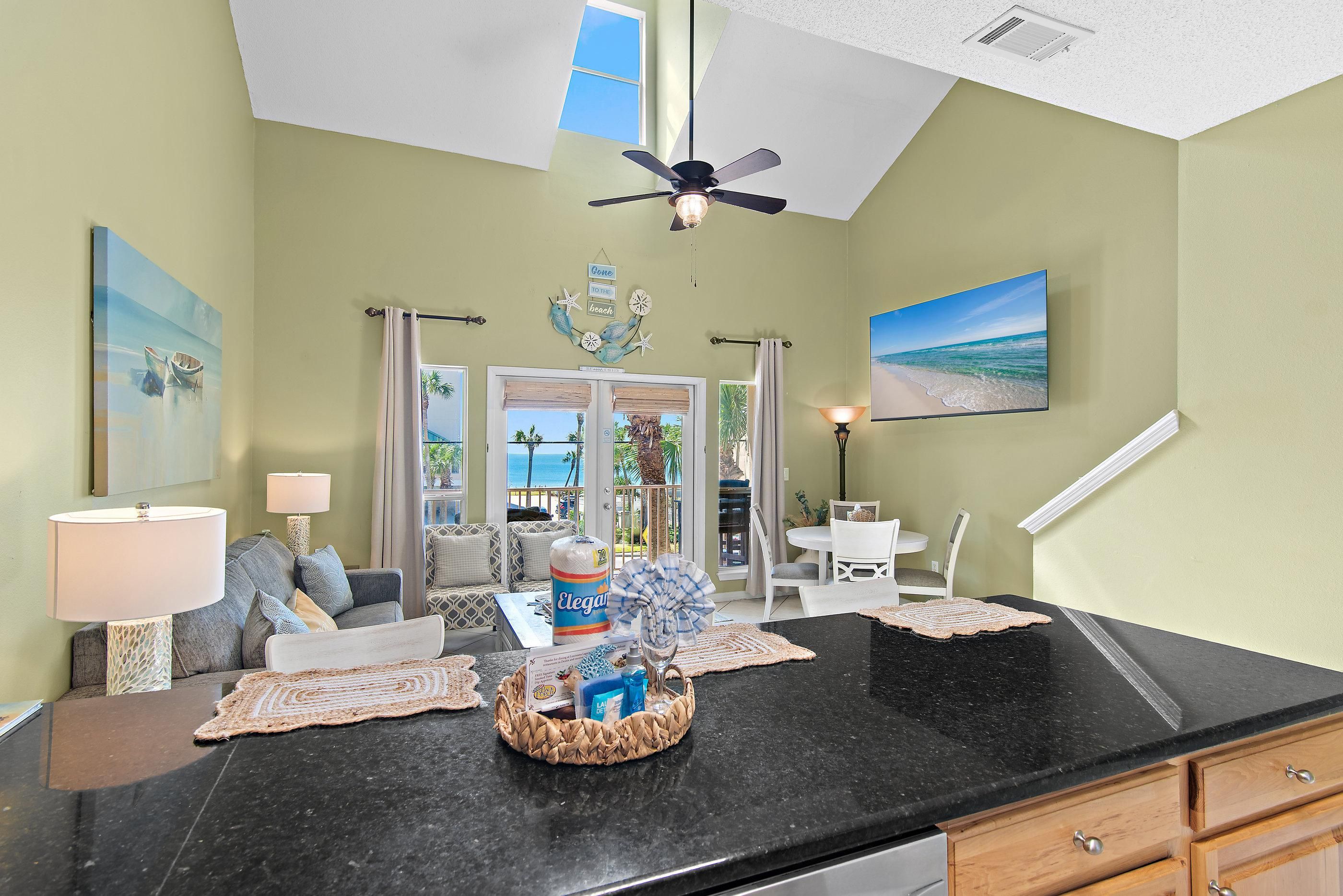 A living room with a black countertop, a ceiling fan, and a view of the ocean through the window.