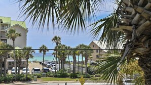 A coastal street with parked cars, palm trees, and a view of the ocean. - Caribbean Dunes 203 (Destin)