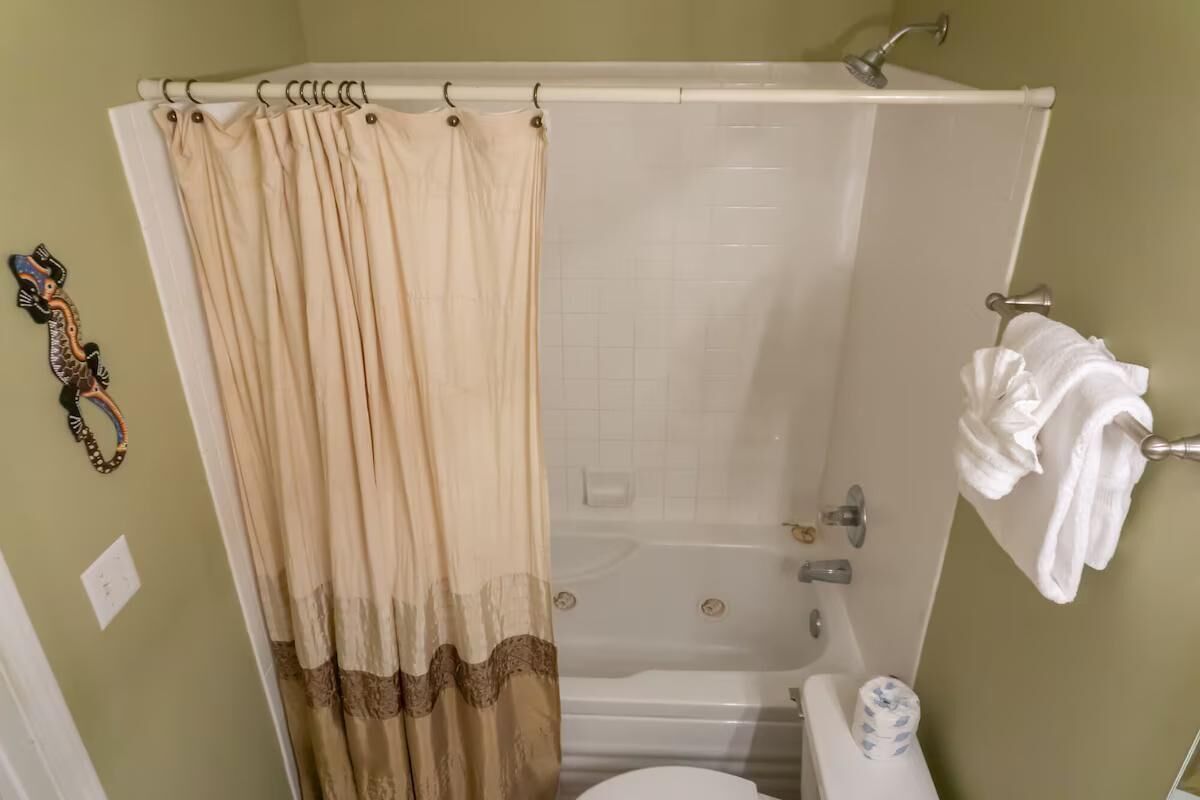 A bathroom with a bathtub, toilet, and shower curtain.