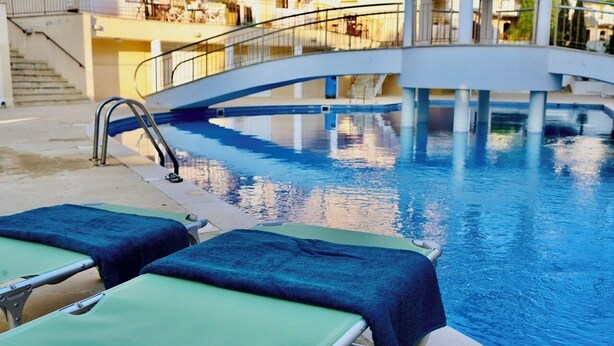 A swimming pool with two lounge chairs, a bridge, and a staircase leading to an upper deck. - Year-Round Sun! COZY 1BR Studio,Long Stays,Remote Workers,Parking, Paphos center (Paphos)