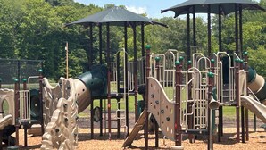 A playground with various play structures, including slides and climbing areas, covered by umbrellas.