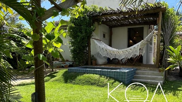 Een gezellig buitenverblijf met een hangmat, een zwembadje en een pergola begroeid met klimplanten.