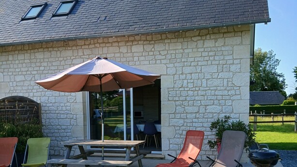 A stone house with a patio, a table, and two chairs.