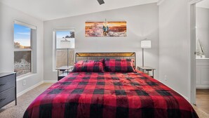 Ein Schlafzimmer mit Bett, Deckenventilator, Fenster und einem Gemälde an der Wand.