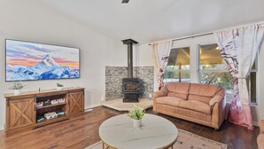 Ein Wohnzimmer mit Steinwand, Kamin, einer Couch, einem Fernseher und einem Holzschrank.