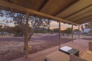 An outdoor patio with wooden flooring, a table, and a chair. - Private Retreat w/ Wi-Fi & Firepit Near Grand Canyon Railway and South Rim (Williams)