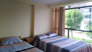 A hotel room with two beds, a window with curtains, and a view of the outside. - Hatun Quilla Apartments (Cusco)