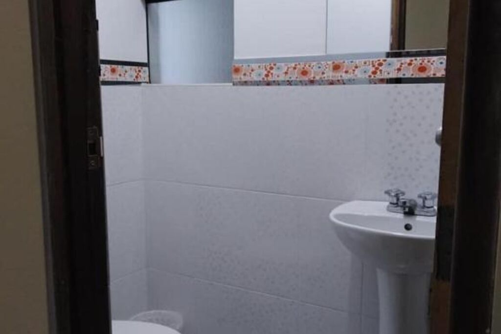 A bathroom with a white sink, a toilet, and a tiled wall.