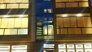 A multi-story building with illuminated windows, a central vertical structure, and a mix of glass and brick facade. - Hatun Quilla Apartments (Cusco)