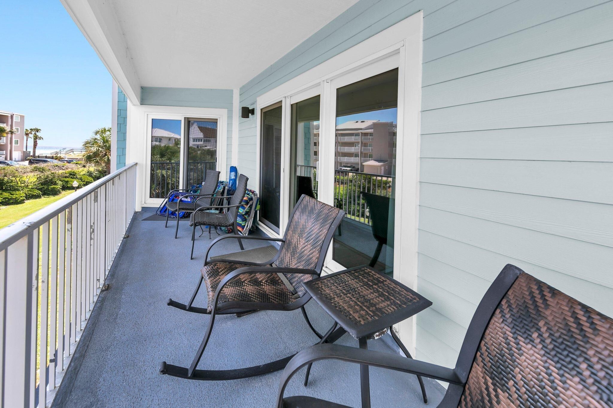 A balcony with outdoor seating, including chairs and a table, overlooking a residential area.