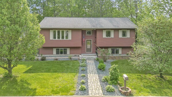 A two-story house with a front porch, a small garden, and a mailbox.