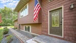 Une maison à deux étages avec un porche à l’avant, un chemin en pierre et un drapeau américain.