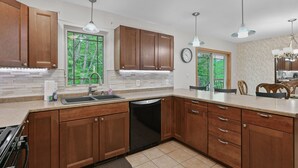 Une cuisine moderne avec des meubles en bois, un grand îlot central et des luminaires suspendus.