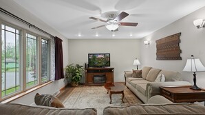 Un salon équipé d’un ventilateur de plafond, d’une télévision, d’un canapé, d’une table basse et d’une lampe.