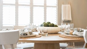 A dining table set with plates, glasses, and a centerpiece of green foliage. - Noc Nest Family Retreat - Screened Lanai - Fire table - Outdoor BBQ - Game Room (Ponte Vedra)