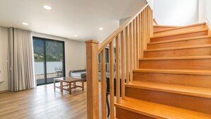 Eine Holztreppe führt zu einem Balkon mit Blick auf eine gebirgige Landschaft.