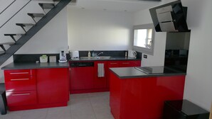 A modern kitchen with red cabinetry, a dishwasher, a coffee maker, and a black refrigerator. - Country house at the gateway to the Limousin-Périgord nature park. (Rilhac-Lastours)