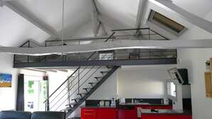 A modern interior with a kitchen, red cabinets, a staircase, and a seating area with patterned cushions. - Country house at the gateway to the Limousin-Périgord nature park. (Rilhac-Lastours)